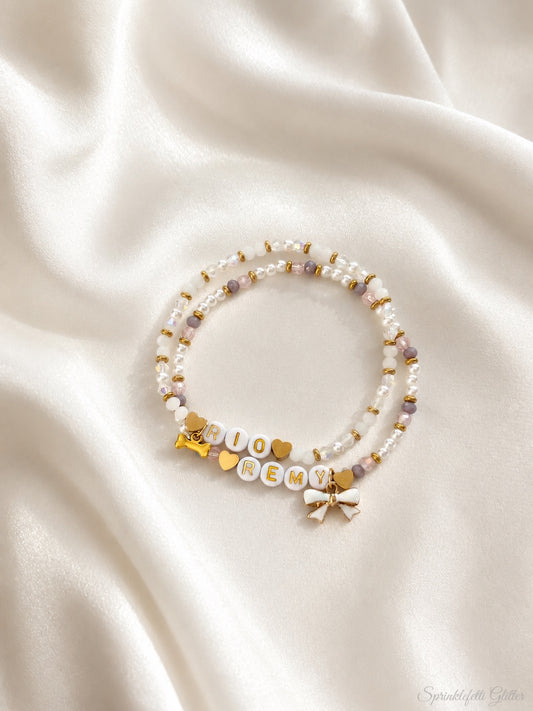 Personalized two-bracelet set with names, hearts, bow, and bone charms